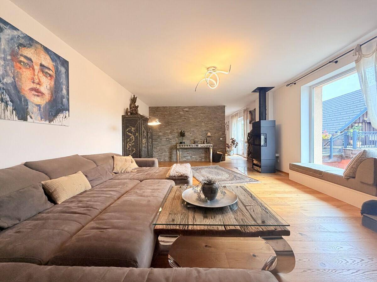 Geräumiges Wohnzimmer mit großem Sofa, Holzboden und modernem Kaminofen.