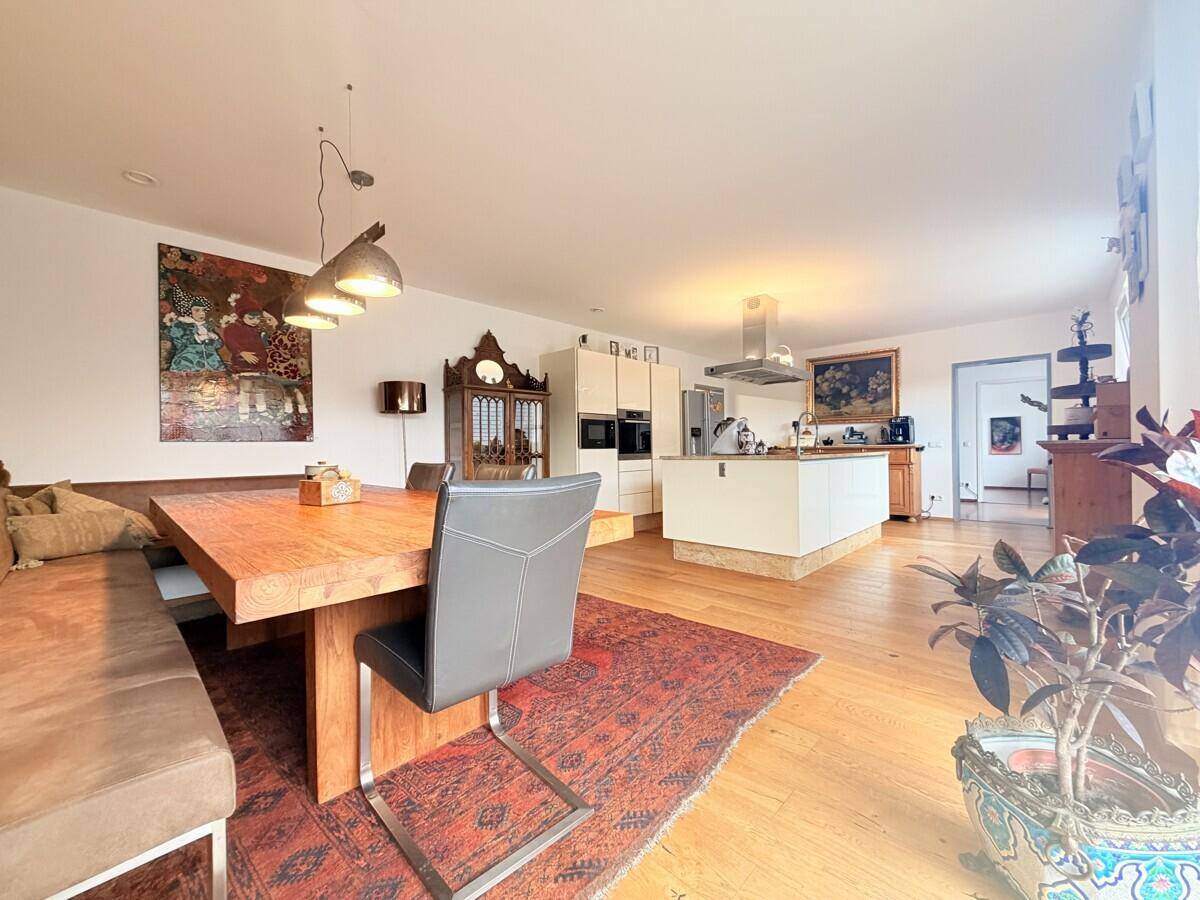 Offener Wohn-Essbereich mit Holztisch, Sitzbank und Blick auf die moderne Küche.