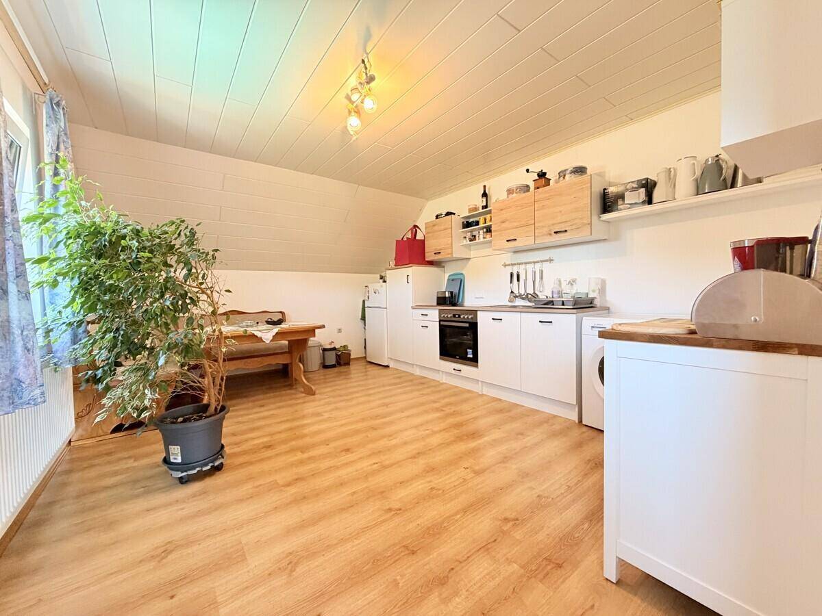 Offene Küche im Dachgeschoss mit Essbereich, Holzboden und schrägen Wänden.