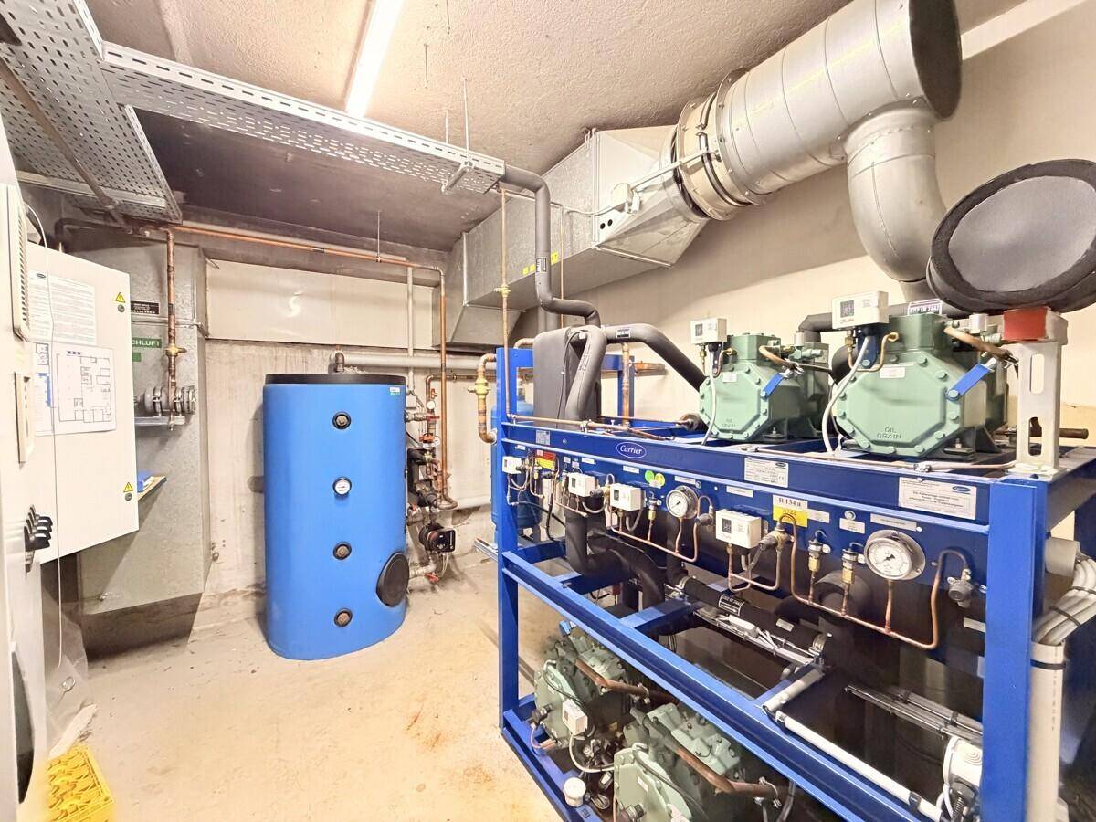 Technikraum mit umfangreichen Anlagen, Rohren und einem großen Warmwasserspeicher für die Versorgung.