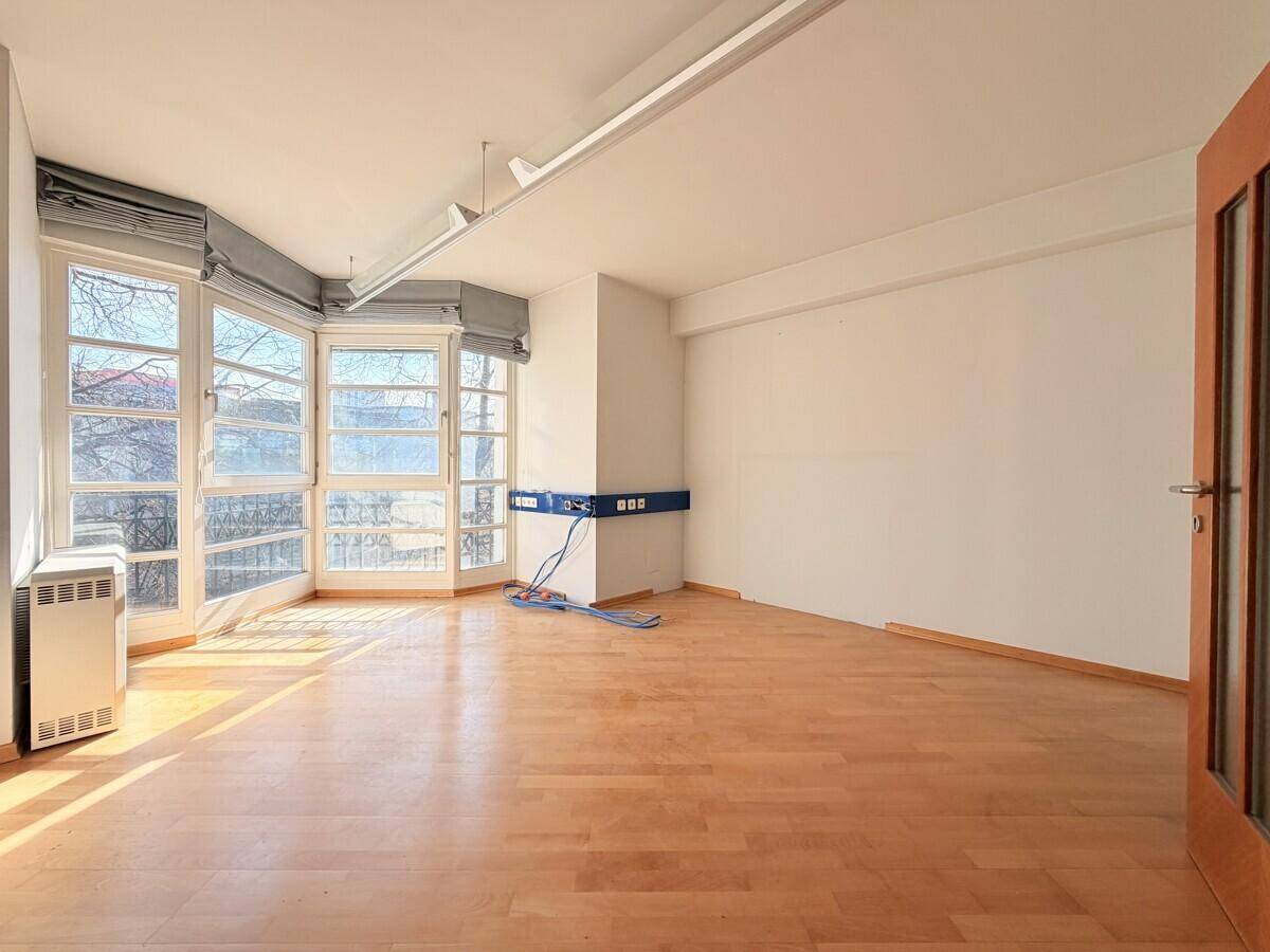 Geräumiger Büroraum mit großen Fenstern, Holzfußboden und viel natürlichem Licht, ideal für produktives Arbeiten.