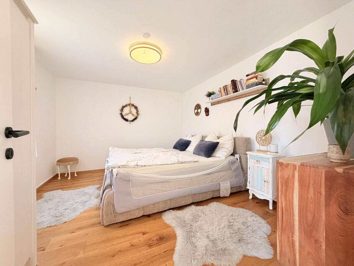 Ruhiges Schlafzimmer mit Holzboden, weiß gestrichenen Wänden und einem großen Bett.