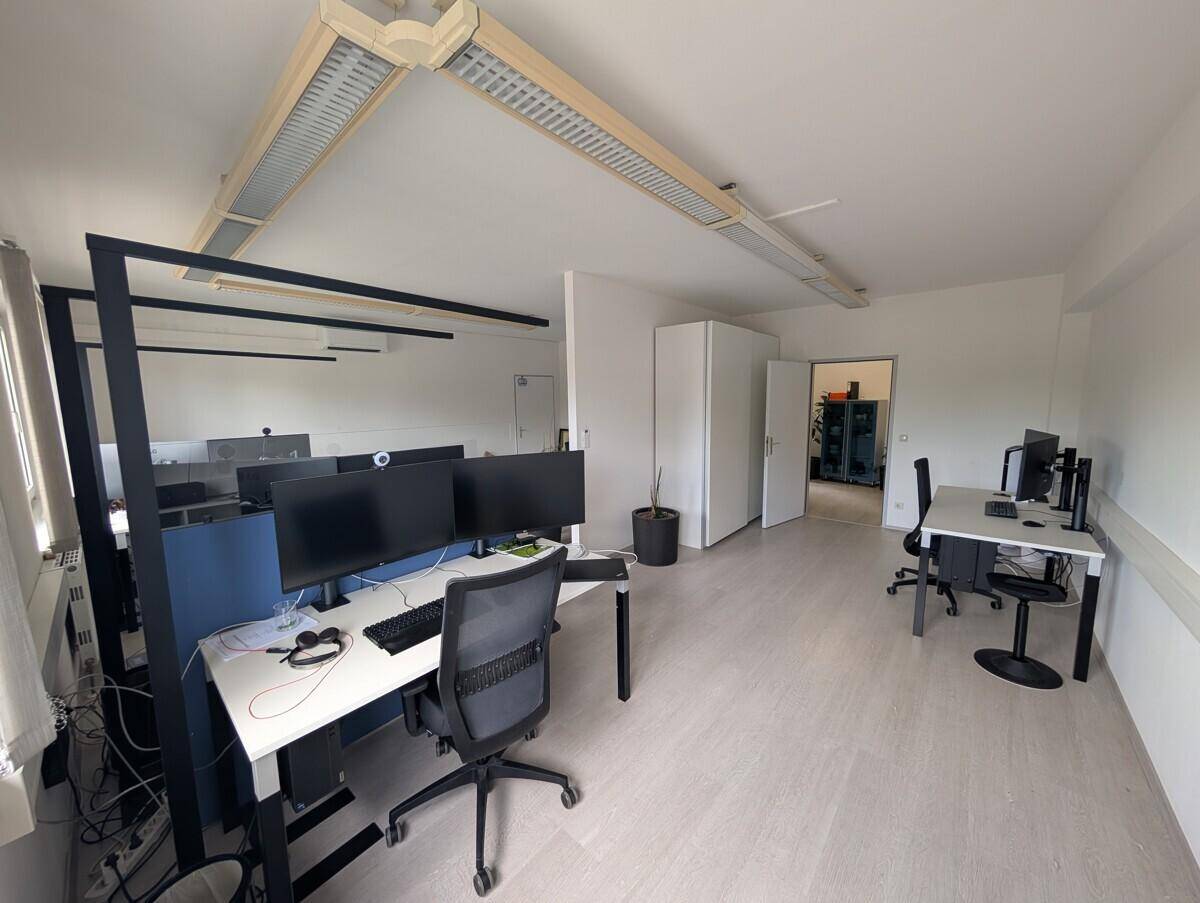 Großes, offenes Büro mit mehreren Arbeitsplätzen, modernen Monitoren und funktionaler Beleuchtung.