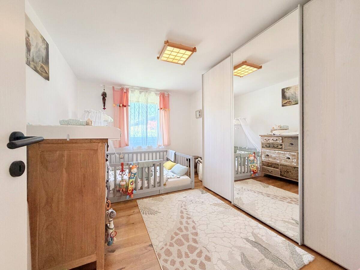 Kinderzimmer mit Holzboden, Babybett und einem großen Spiegelschrank.