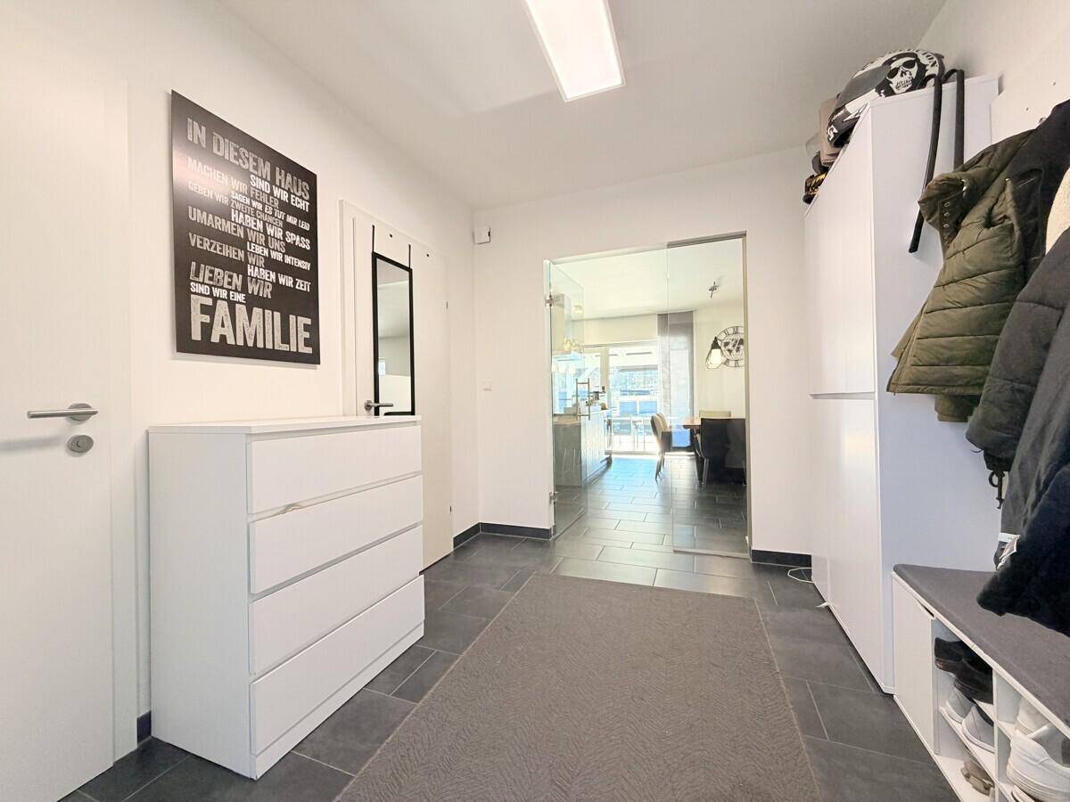 Heller Eingangsbereich mit Garderobe, Kommode und Glastür zum offenen Wohnbereich.