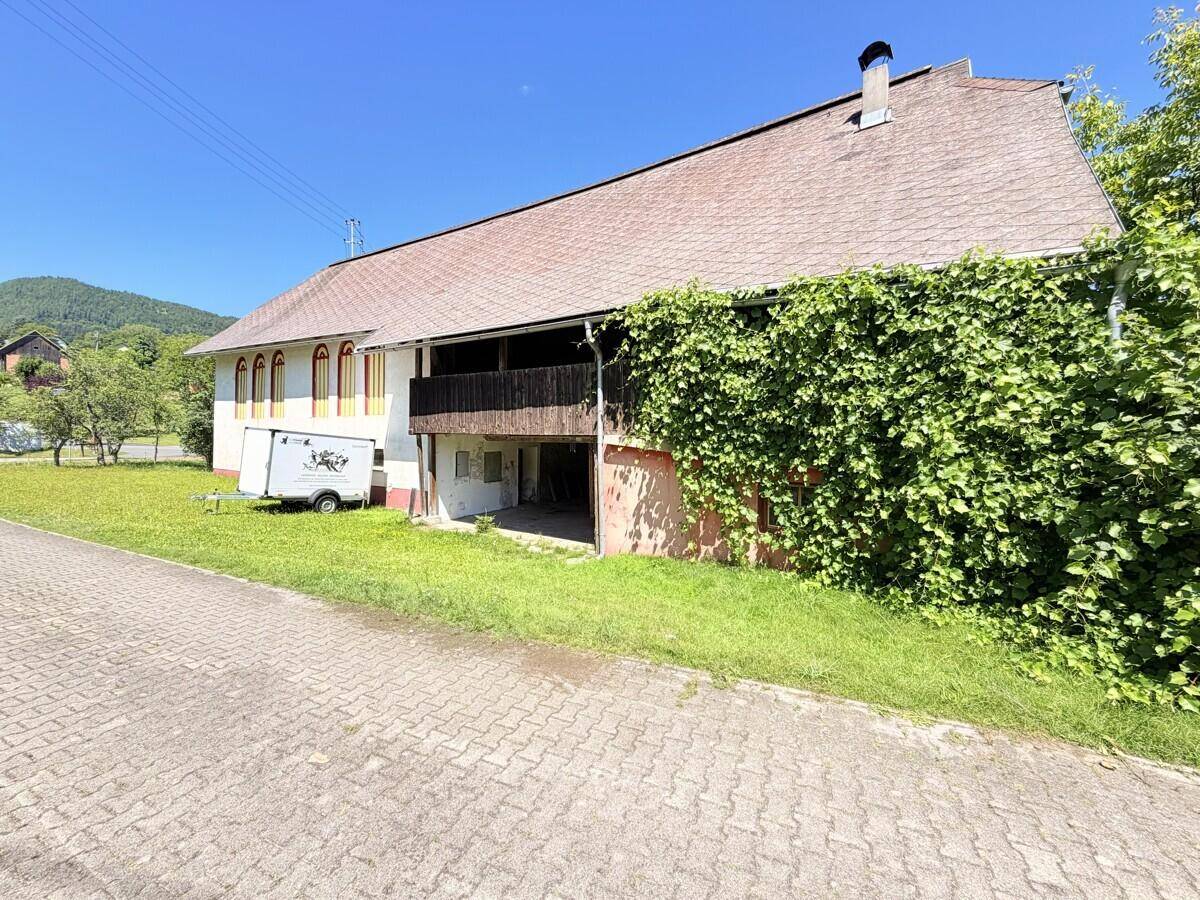 Seitenansicht des Gebäudes mit bewachsener Fassade und überdachtem Balkonbereich.