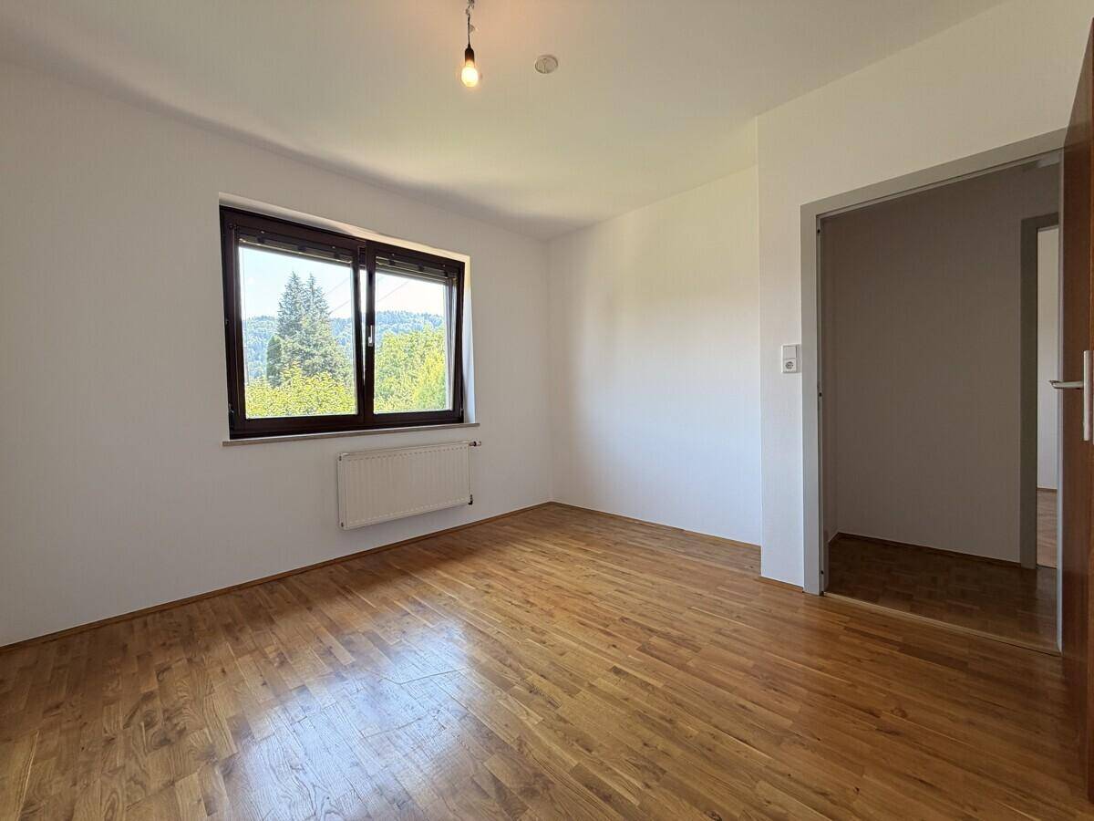 Helles Zimmer mit glänzendem Parkettboden und weitem Blick ins Grüne.