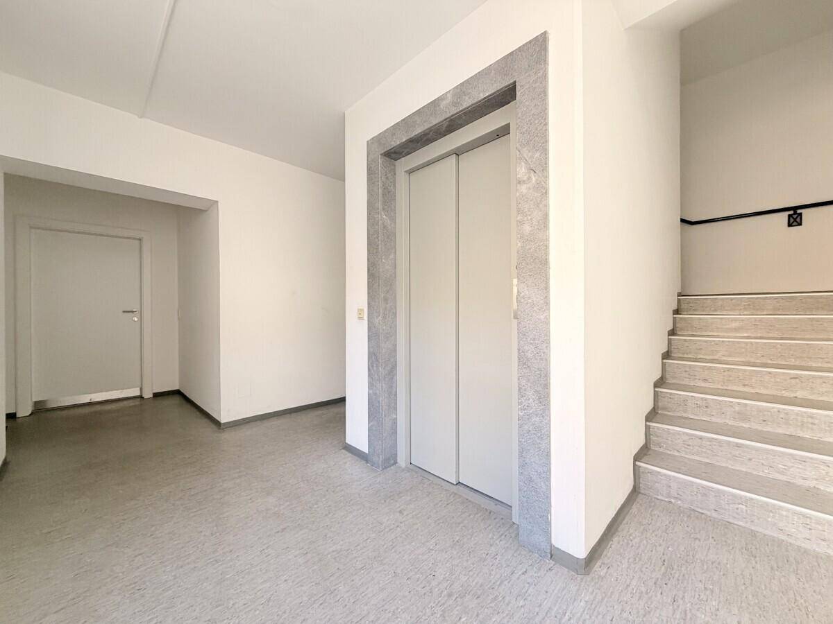 Eingangsbereich mit modernem Aufzug und Treppenhaus, ausgestattet mit hellem Boden und klaren Linien.