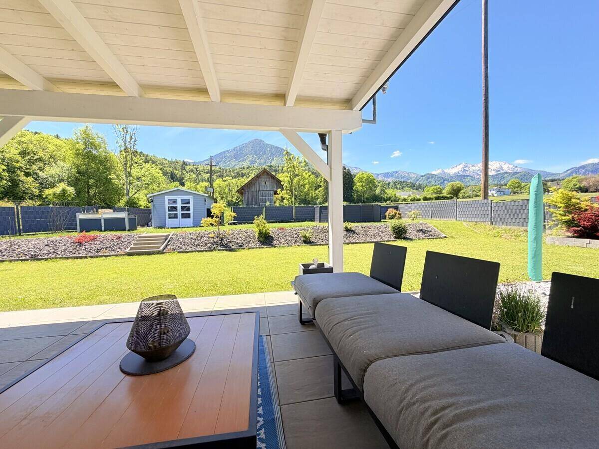 Gemütliche Lounge-Ecke auf der überdachten Terrasse mit Blick auf den Garten und die Berge.