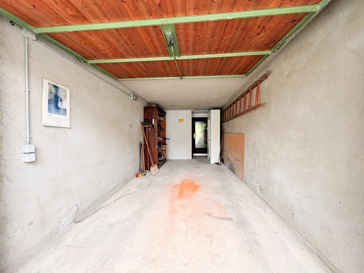 Geräumige Garage mit Betonboden und Holzdecke, bietet Platz für ein Fahrzeug und Lagerung.