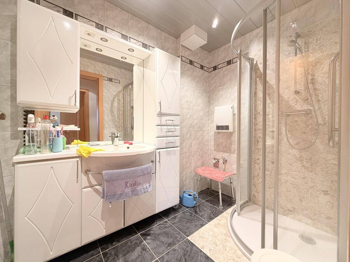 Badezimmer mit Duschkabine, Waschtisch und Spiegelschrank.