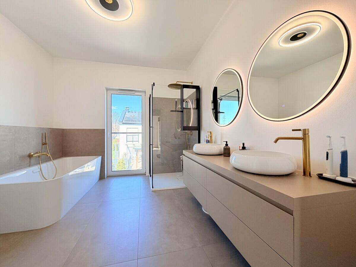 Luxuriöses Badezimmer mit Doppelwaschbecken, Badewanne, begehbarer Dusche und modernen Armaturen.