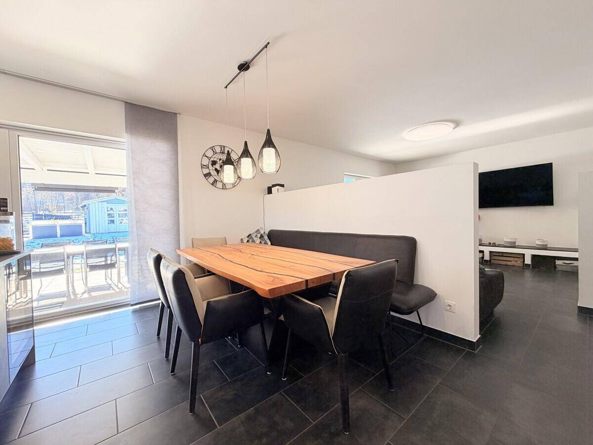 Moderner Essbereich mit Holztisch und Sitzbank, offen zum Wohnbereich und Küche.