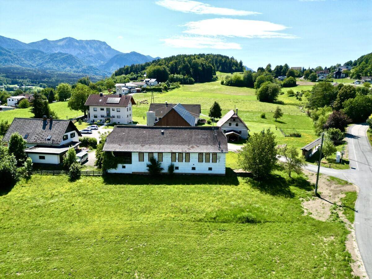 Rückansicht des Anwesens mit weiten Grünflächen und benachbarten Gebäuden.