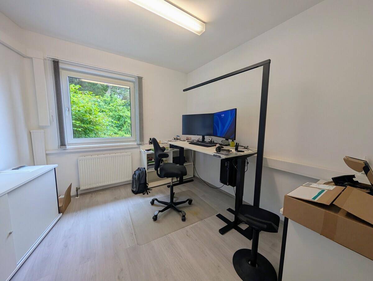 Einzelner Arbeitsplatz in einem Büro mit großem Fenster und Blick ins Grüne.