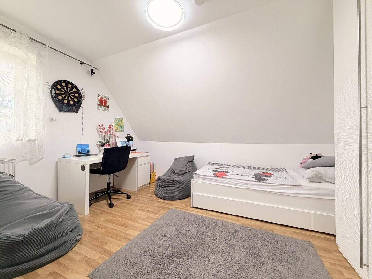 Kinderzimmer im Dachgeschoss mit Bett, Schreibtisch, Laminatboden und Dachschräge.