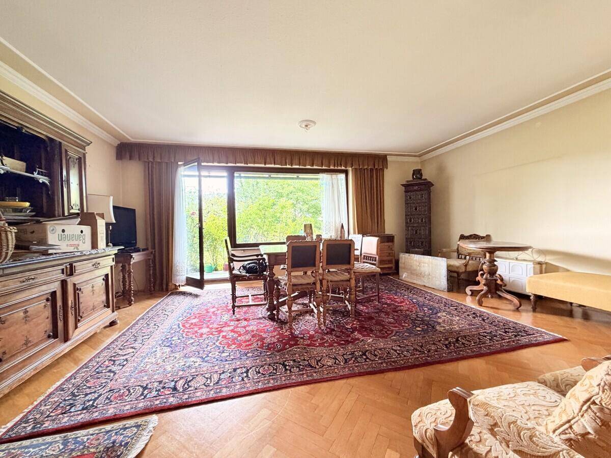 Geräumiger Wohn-Essbereich mit traditionellen Holzmöbeln, großem Teppich und Zugang zur Terrasse.