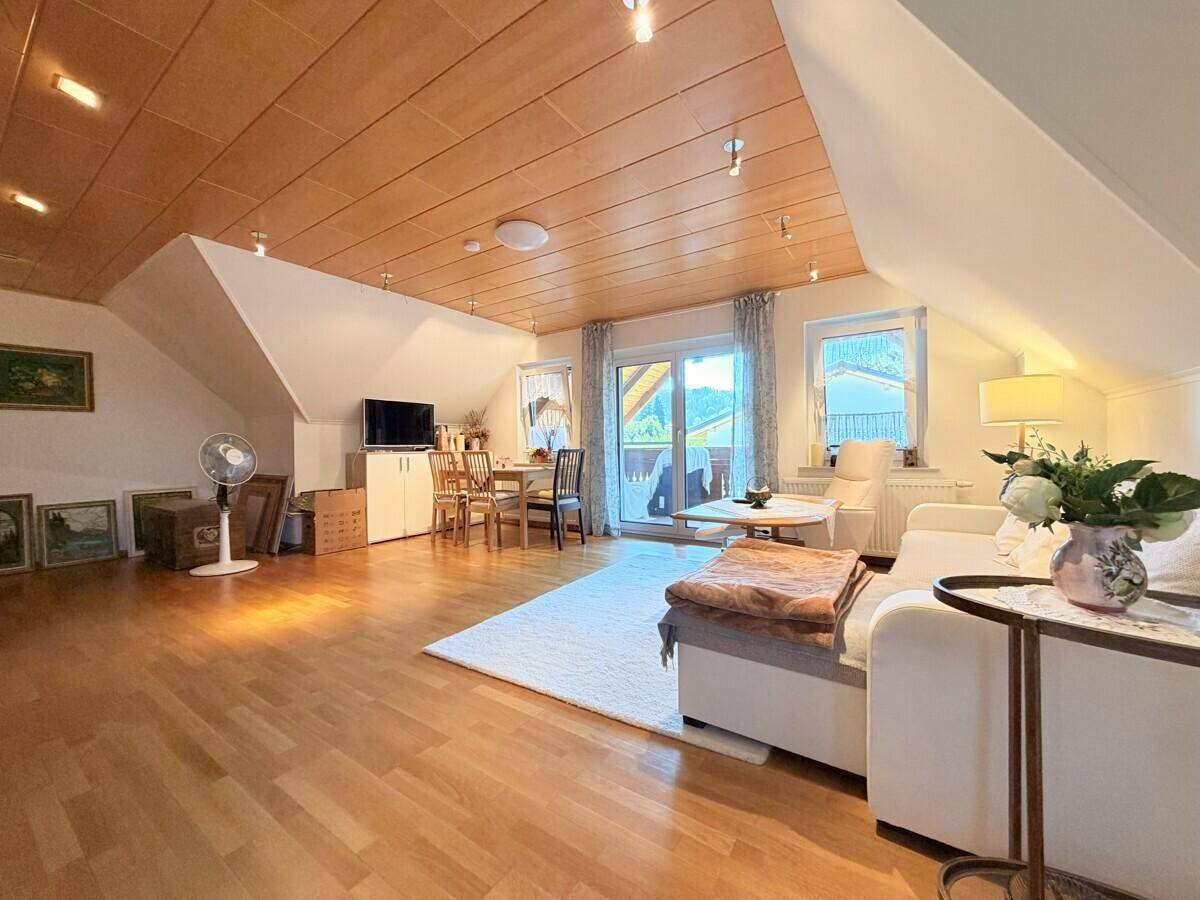 Geräumiger Wohn-Essbereich im Dachgeschoss mit Holzboden und Zugang zum Balkon.