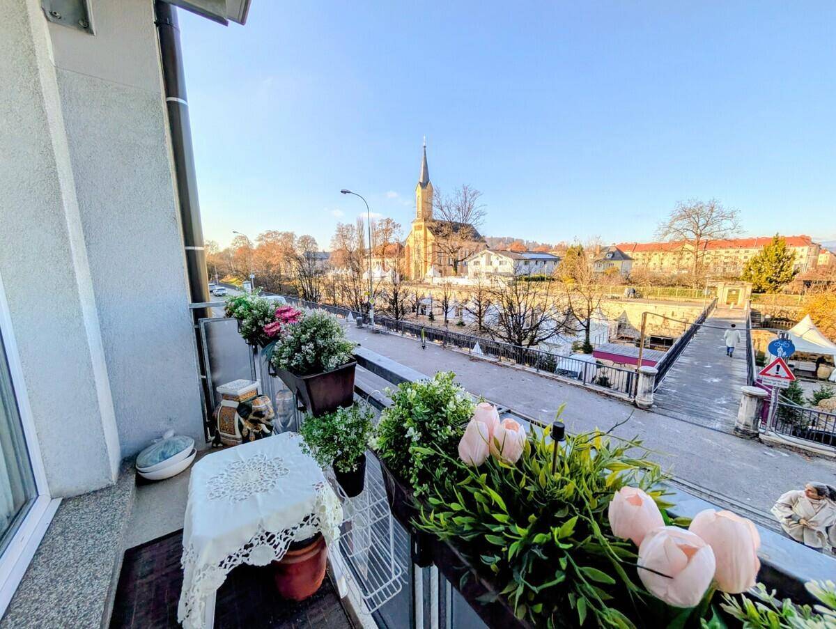 Sonnenverwöhnter Balkon mit Pflanzen und weitem Blick auf eine Kirche und die Stadt.