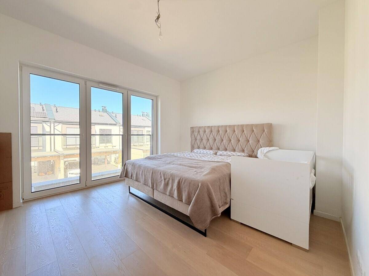 Geräumiges Schlafzimmer mit Doppelbett, Holzboden und großen Fenstern mit Blick nach draußen.