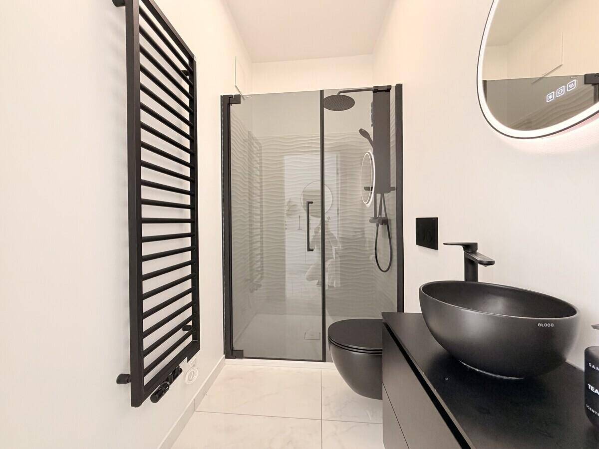 Modernes Badezimmer mit schwarzer Ausstattung, begehbarer Dusche und beheiztem Handtuchhalter.