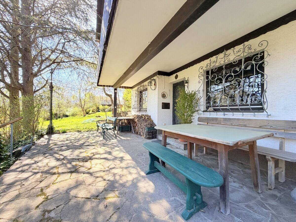 Gepflasterte Terrasse mit rustikalen Gartenmöbeln und Zugang zum Gartenbereich des Hauses.