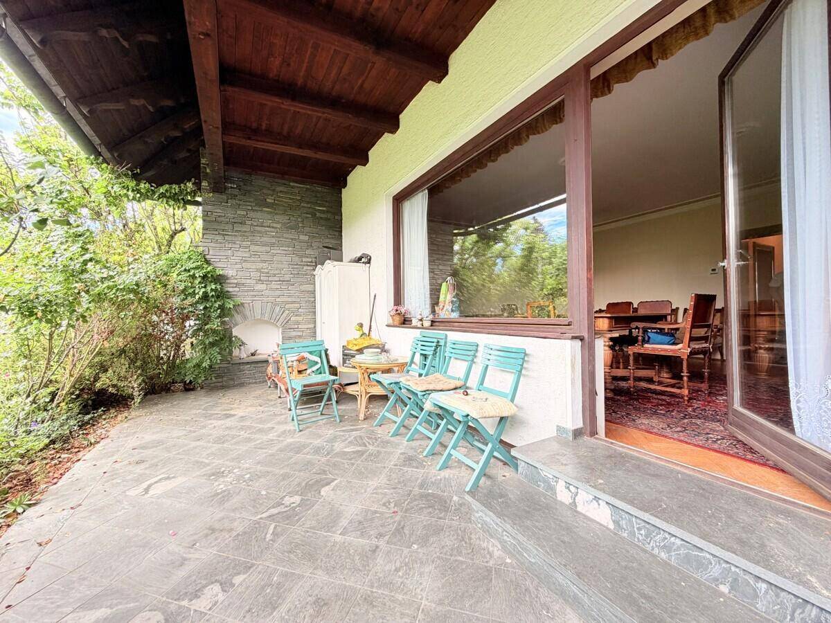 Überdachte Terrasse mit Steinfliesen und rustikalen Gartenmöbeln, ideal für entspannte Stunden im Freien.