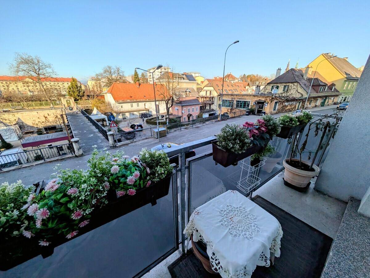 Gemütlicher Balkon mit Blumenkästen und Blick auf die Straße und umliegende Häuser.