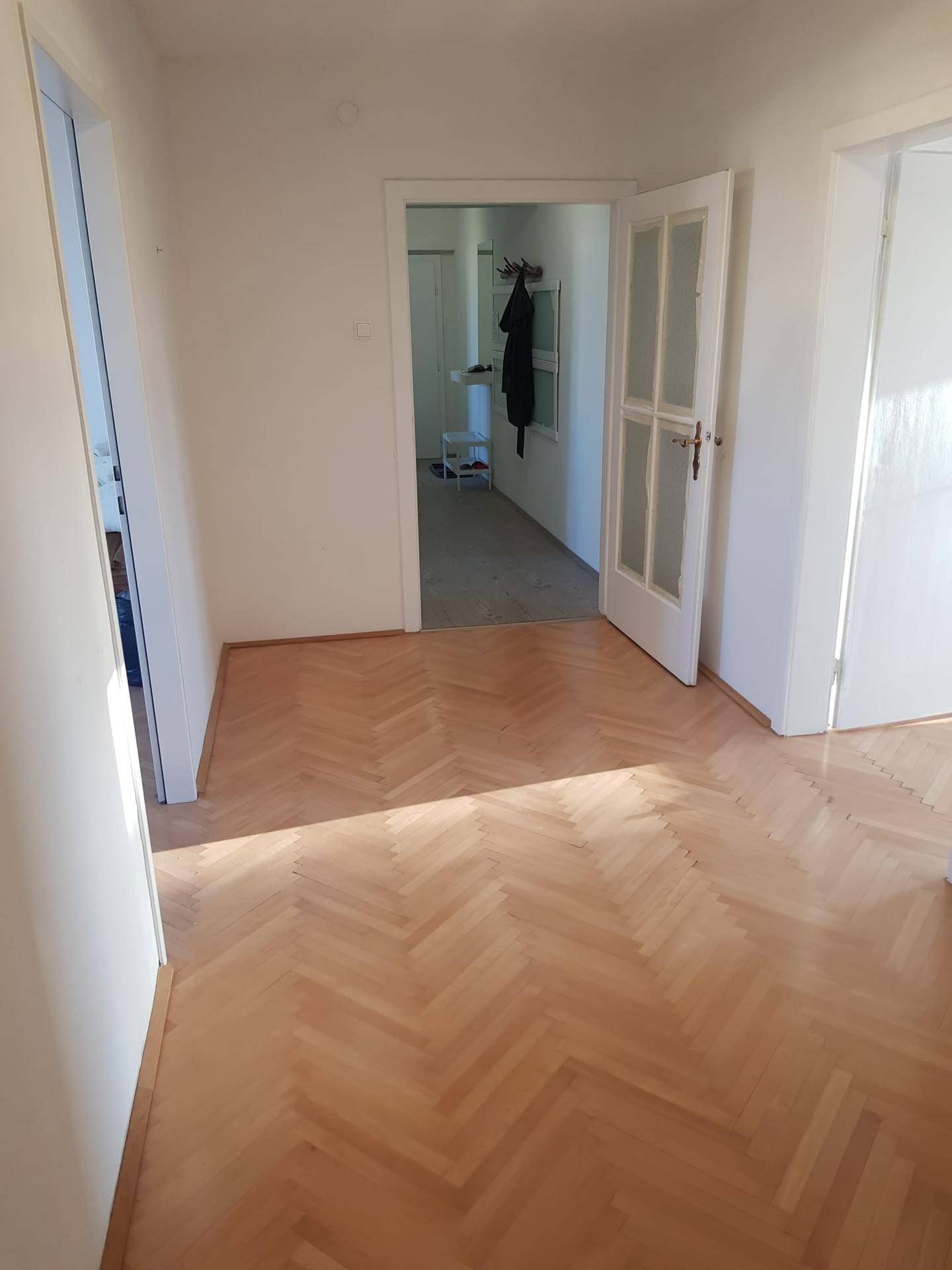 Geräumiger Flur mit elegantem Fischgrätparkett, der zu verschiedenen Wohnbereichen führt.