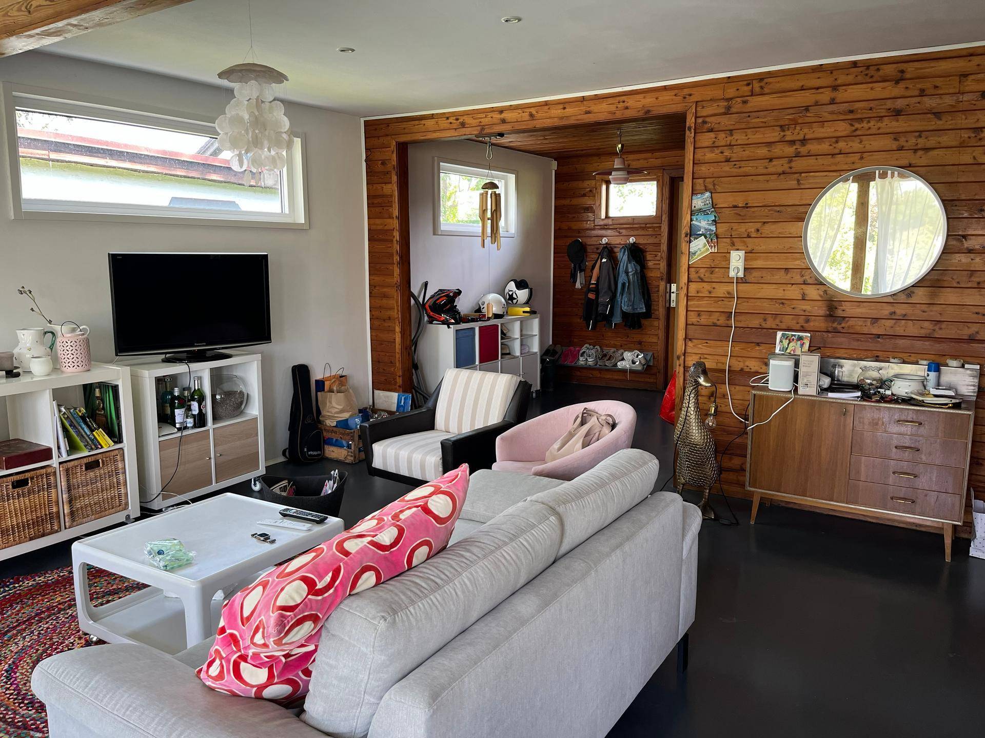 Wohnzimmer mit Holzwänden, bequemen Sofas und Blick auf den Außenbereich durch die Fenster.