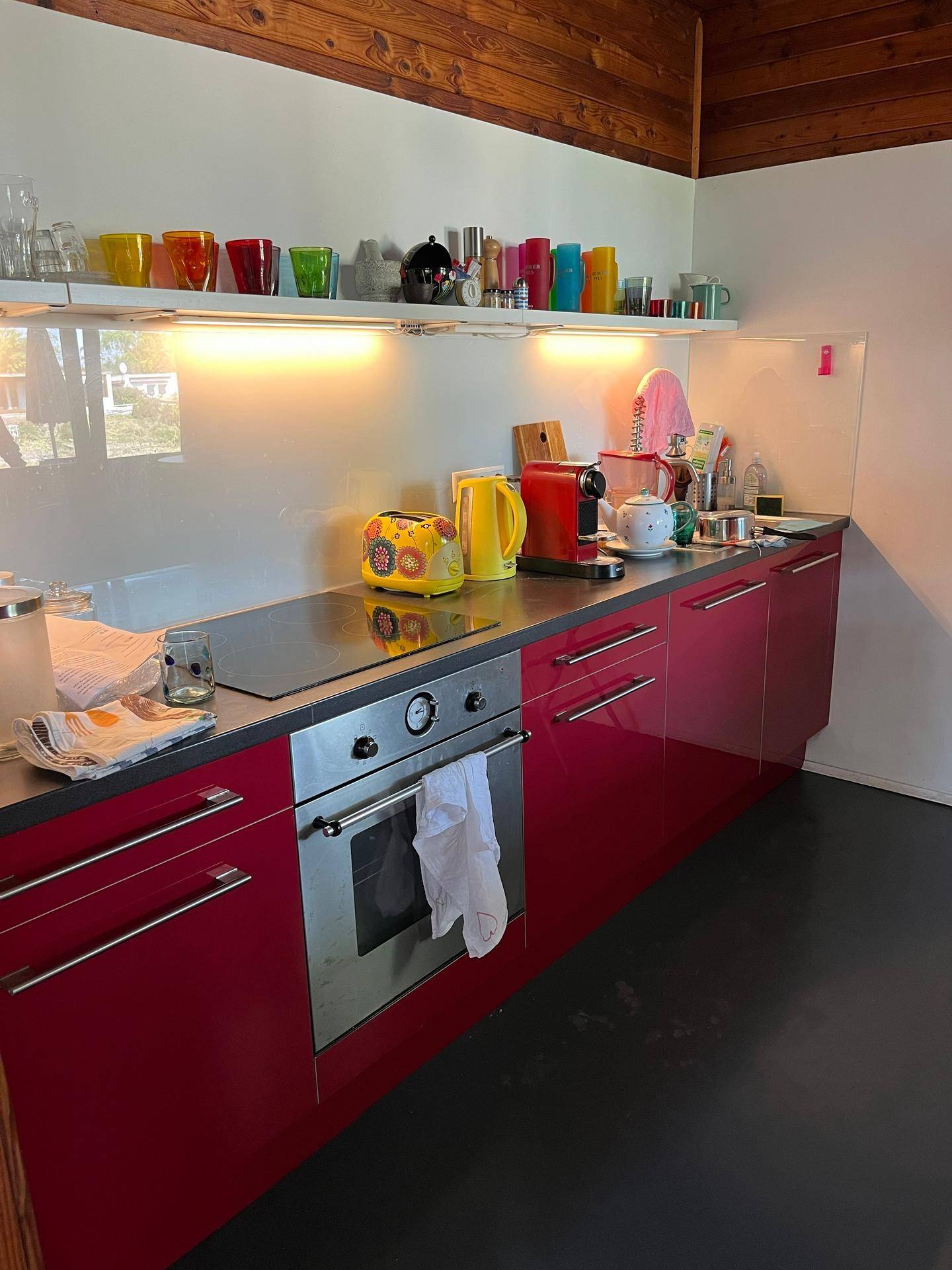 Moderne Küche mit roten Hochglanzfronten, Induktionskochfeld und bunten Accessoires.