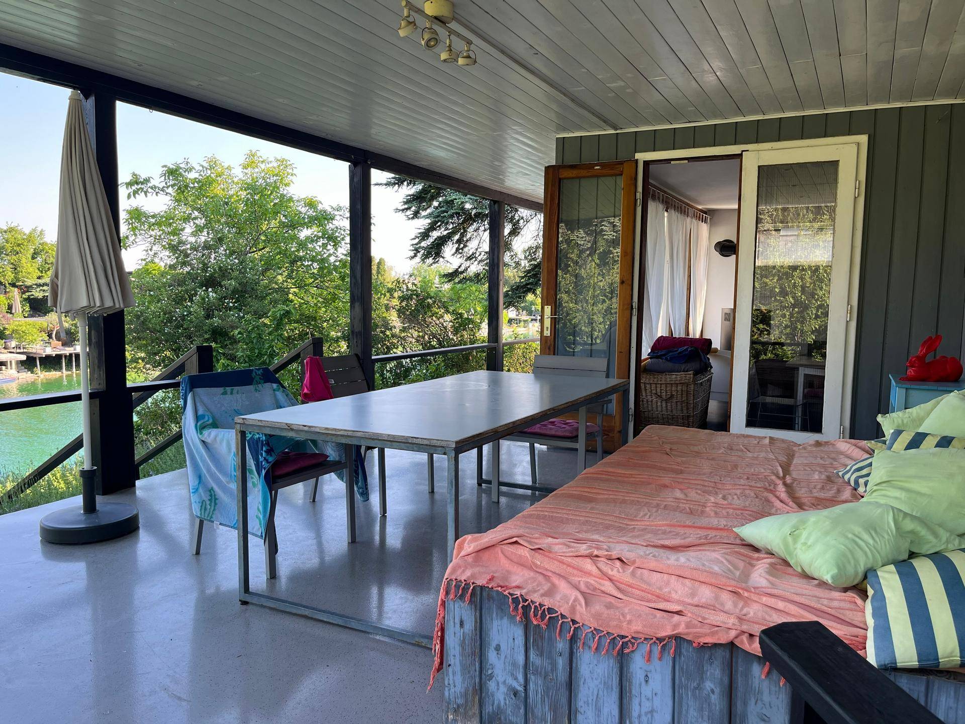Geräumige überdachte Terrasse mit Esstisch und Blick auf das Wasser, ideal zum Entspannen.