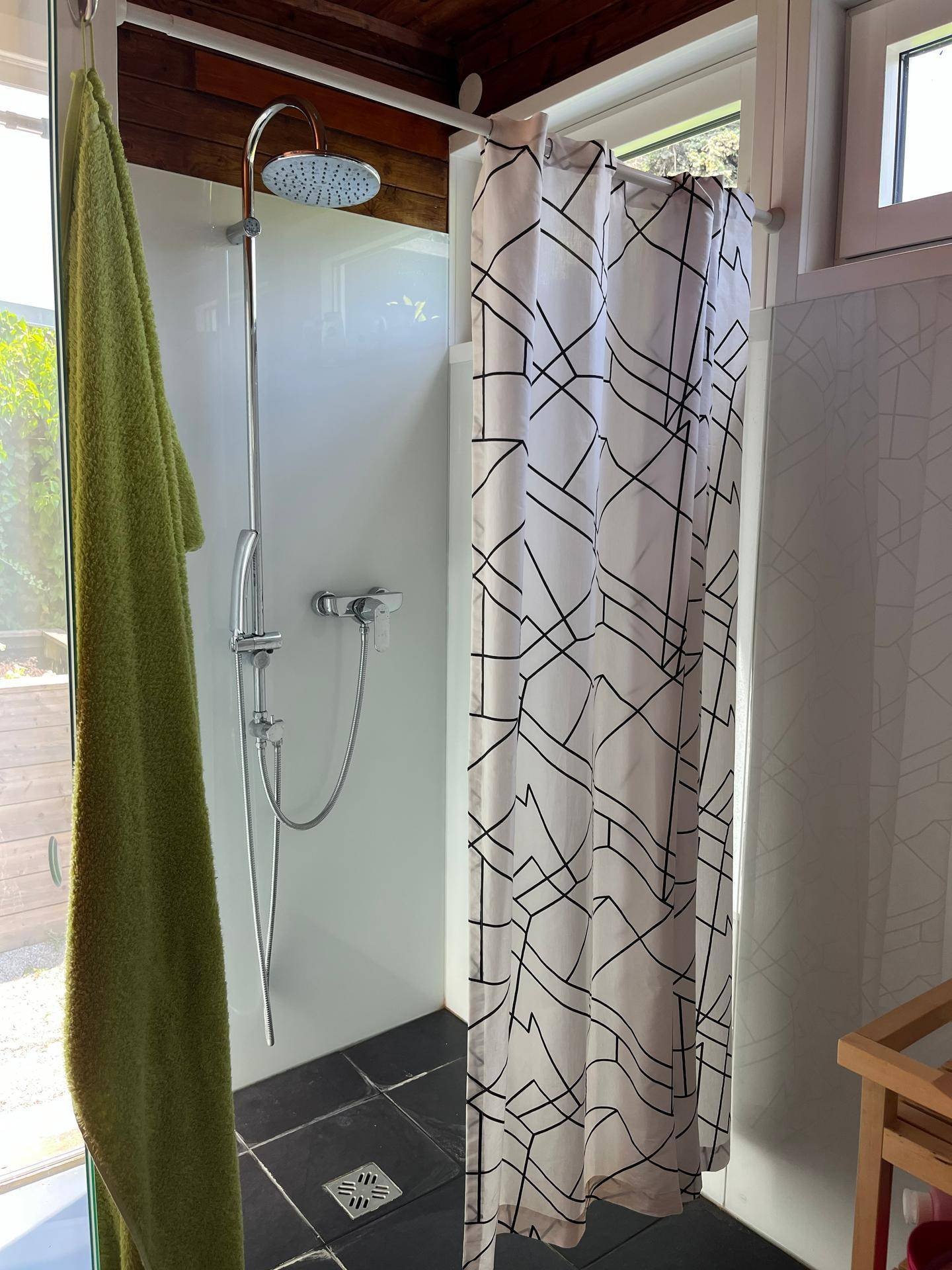 Helle Duschkabine mit Regendusche und modernem Duschvorhang in einem kleinen Bad.