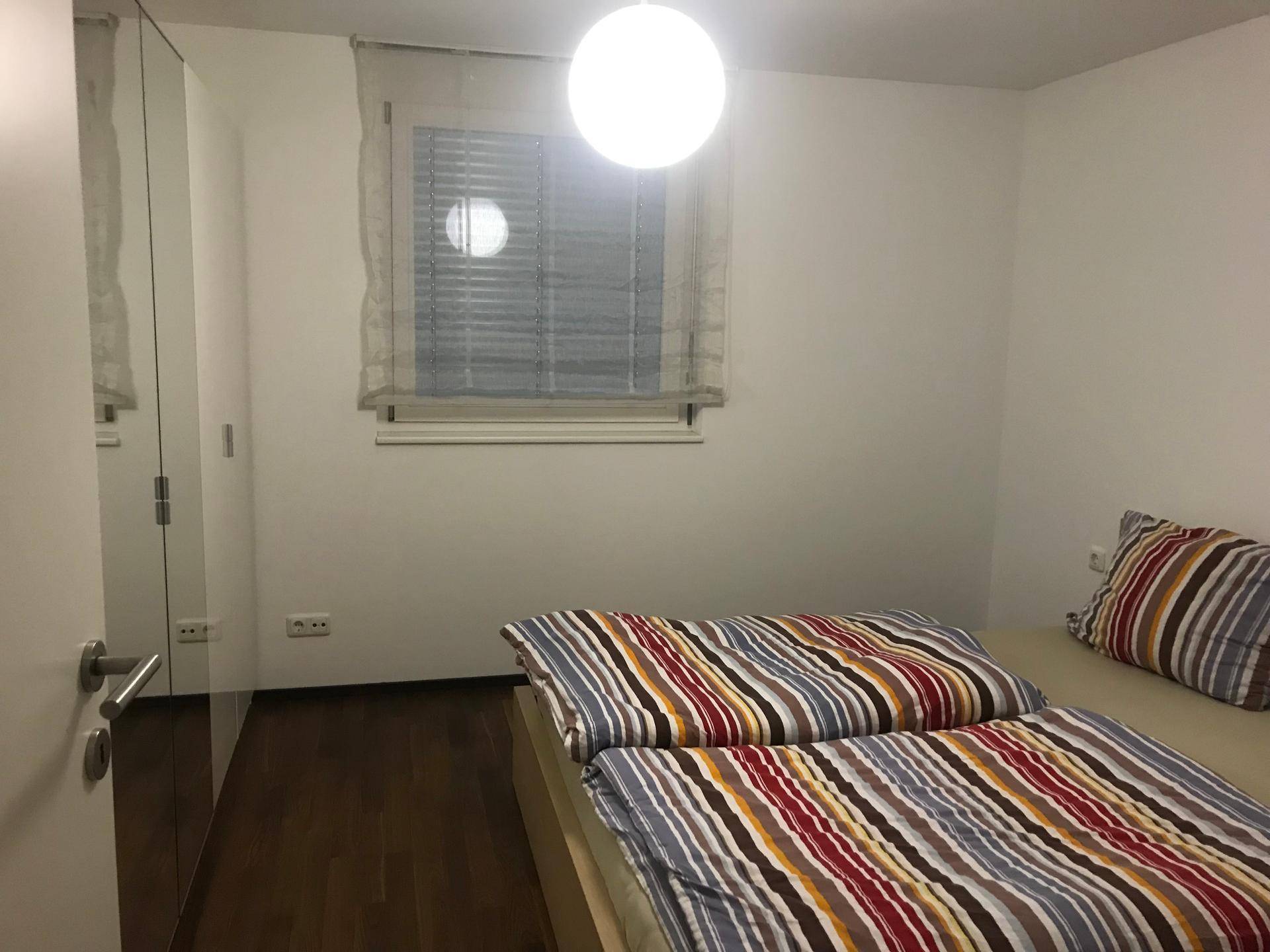 Gemütliches Schlafzimmer mit Bett, Fenster und einem Spiegelschrank, bietet Komfort.