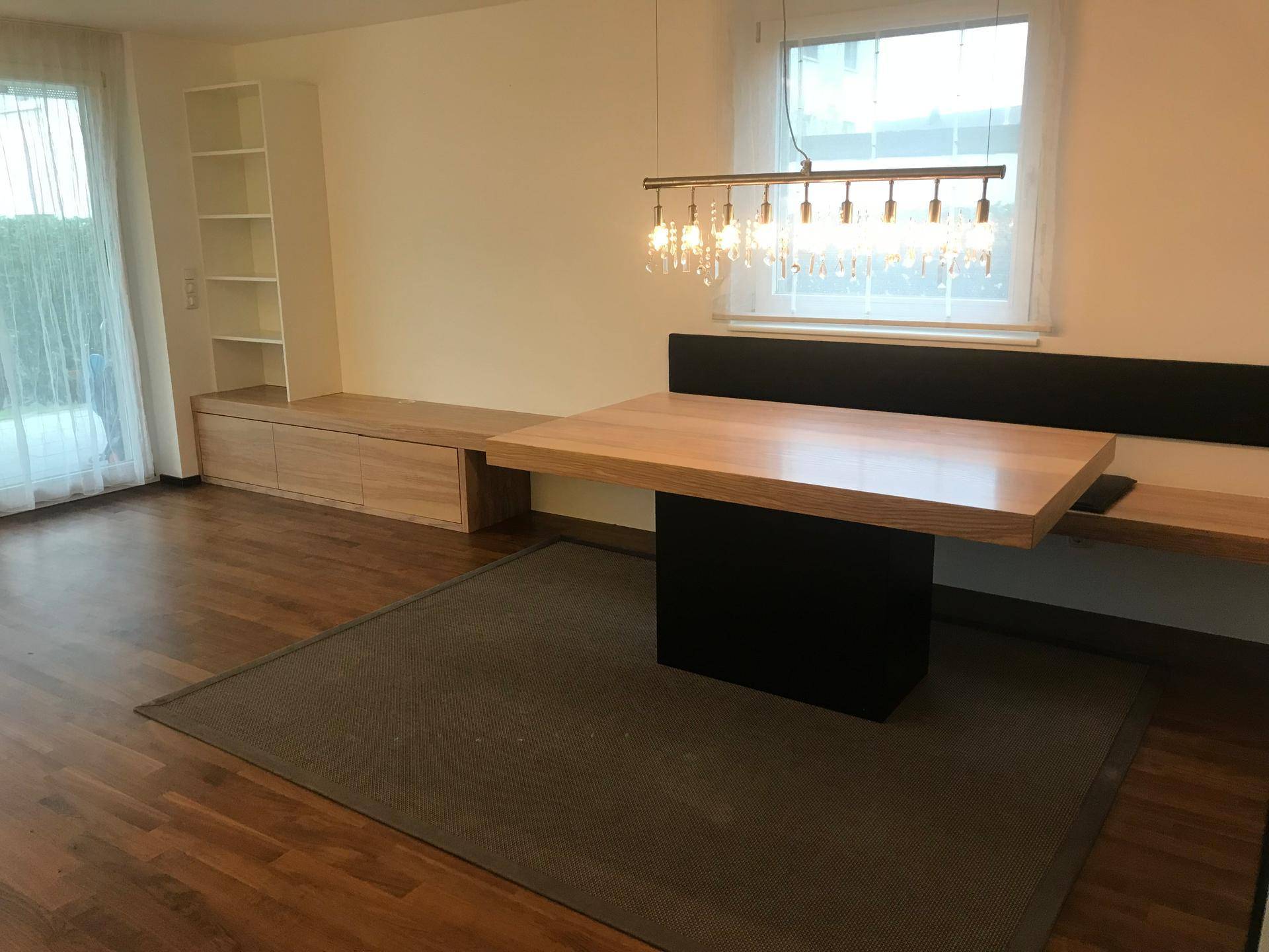 Geräumiger Essbereich mit Holztisch, integrierter Sitzbank und Regalen, mit Zugang zum Garten.