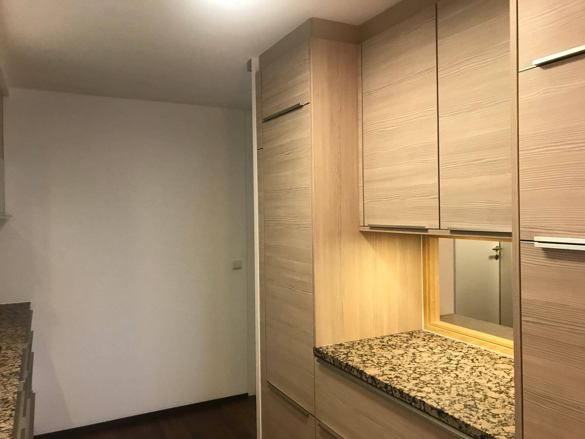 Moderne Küchenzeile mit Holzschränken, Granitarbeitsplatte und praktischer Durchreiche.