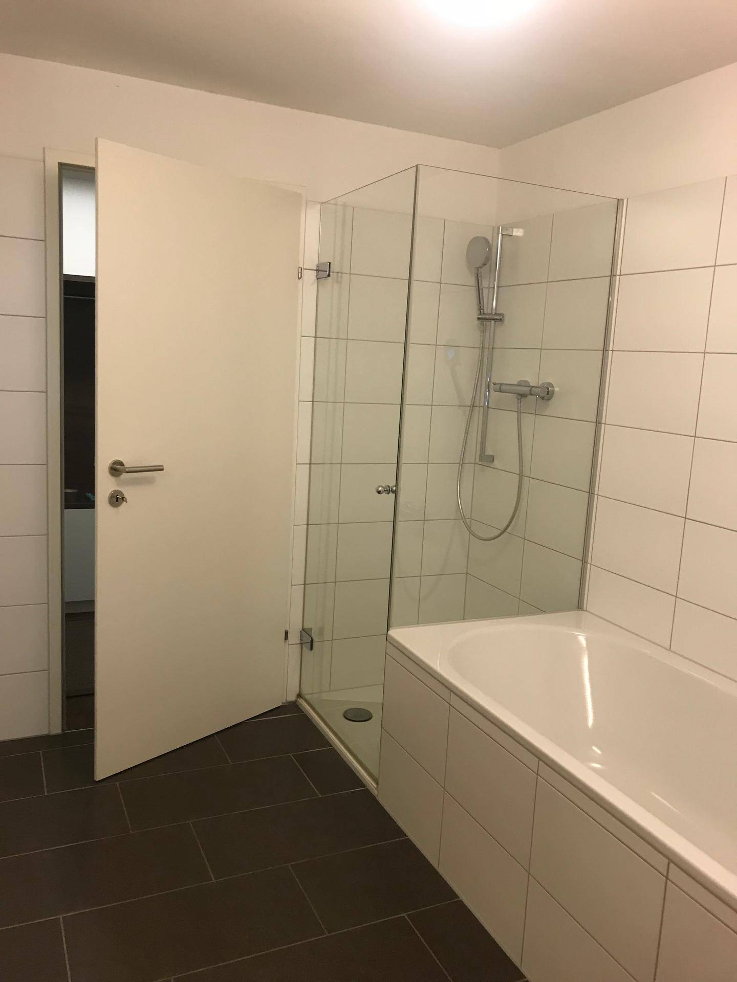 Badezimmer mit Badewanne und moderner begehbarer Dusche mit Glasabtrennung.