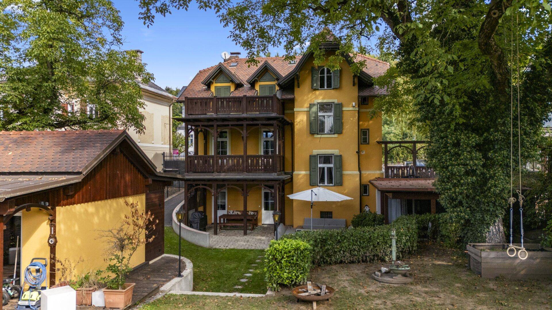 Historische Villa mit gelber Fassade, Balkonen und weitläufigem Gartenbereich.