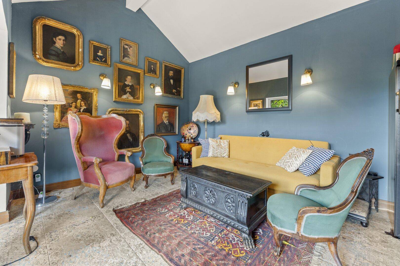Geräumiges Wohnzimmer mit antiken Möbeln, Kunstwerken und hohen Decken.