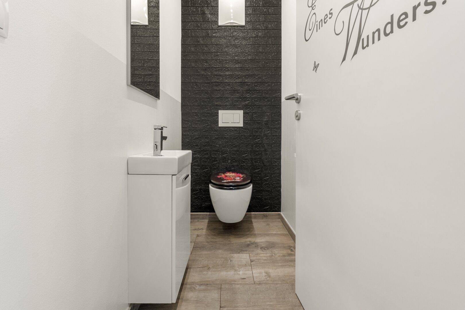 Kleines Gäste-WC mit modernem Design, Wand-WC und dunkler Akzentwand.