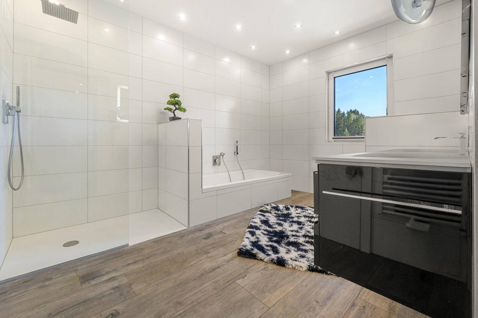 Modernes Badezimmer mit großer begehbarer Dusche, Badewanne und Fenster.