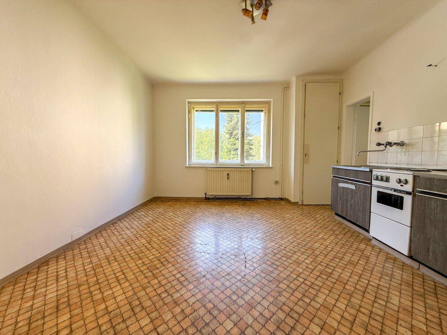 Geräumiger Küchenbereich mit Fenster und einfacher Küchenzeile, bereit zur individuellen Gestaltung.
