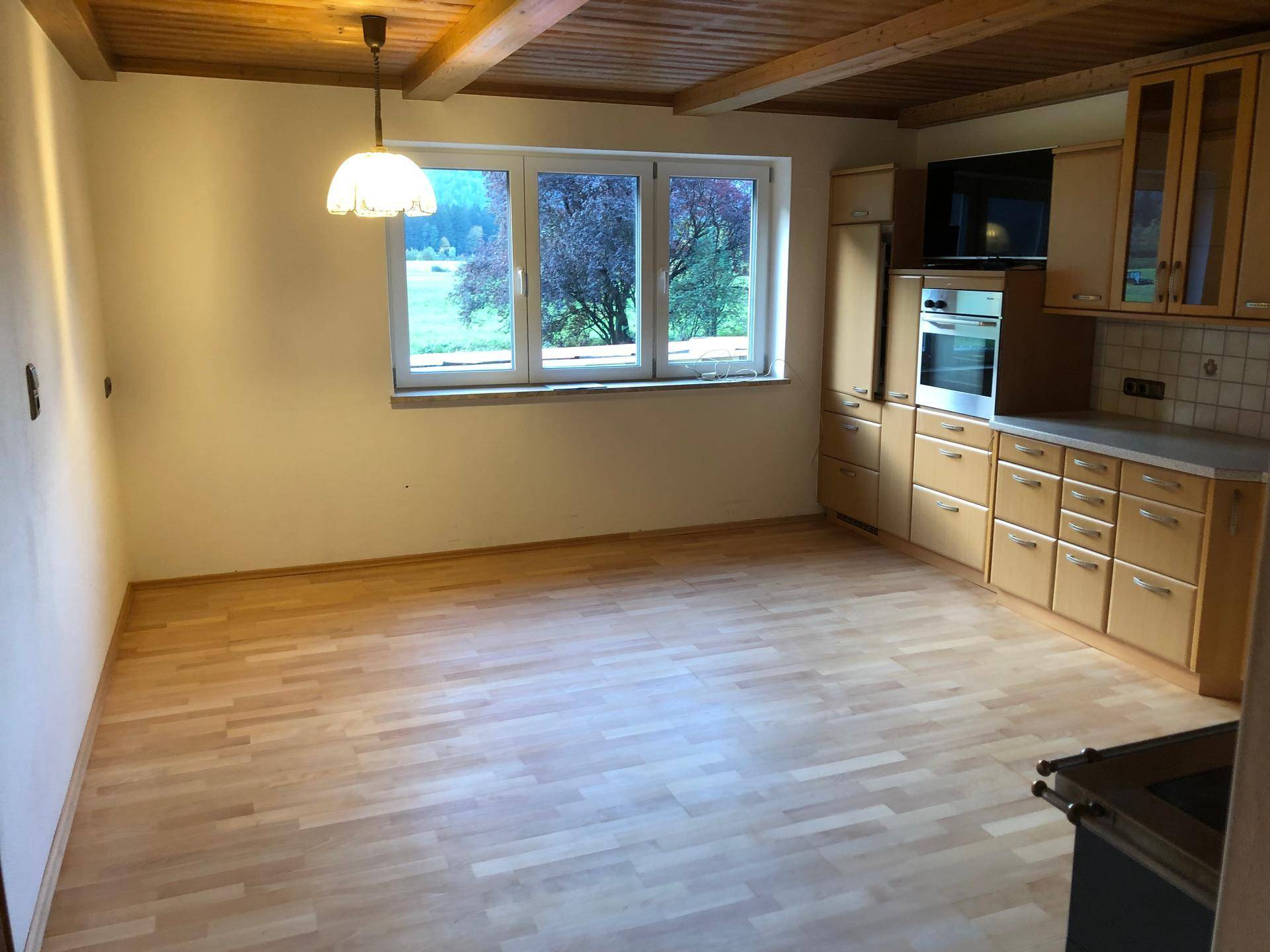 Offener Küchenbereich mit Holzbalkendecke, Laminatboden und viel Tageslicht.