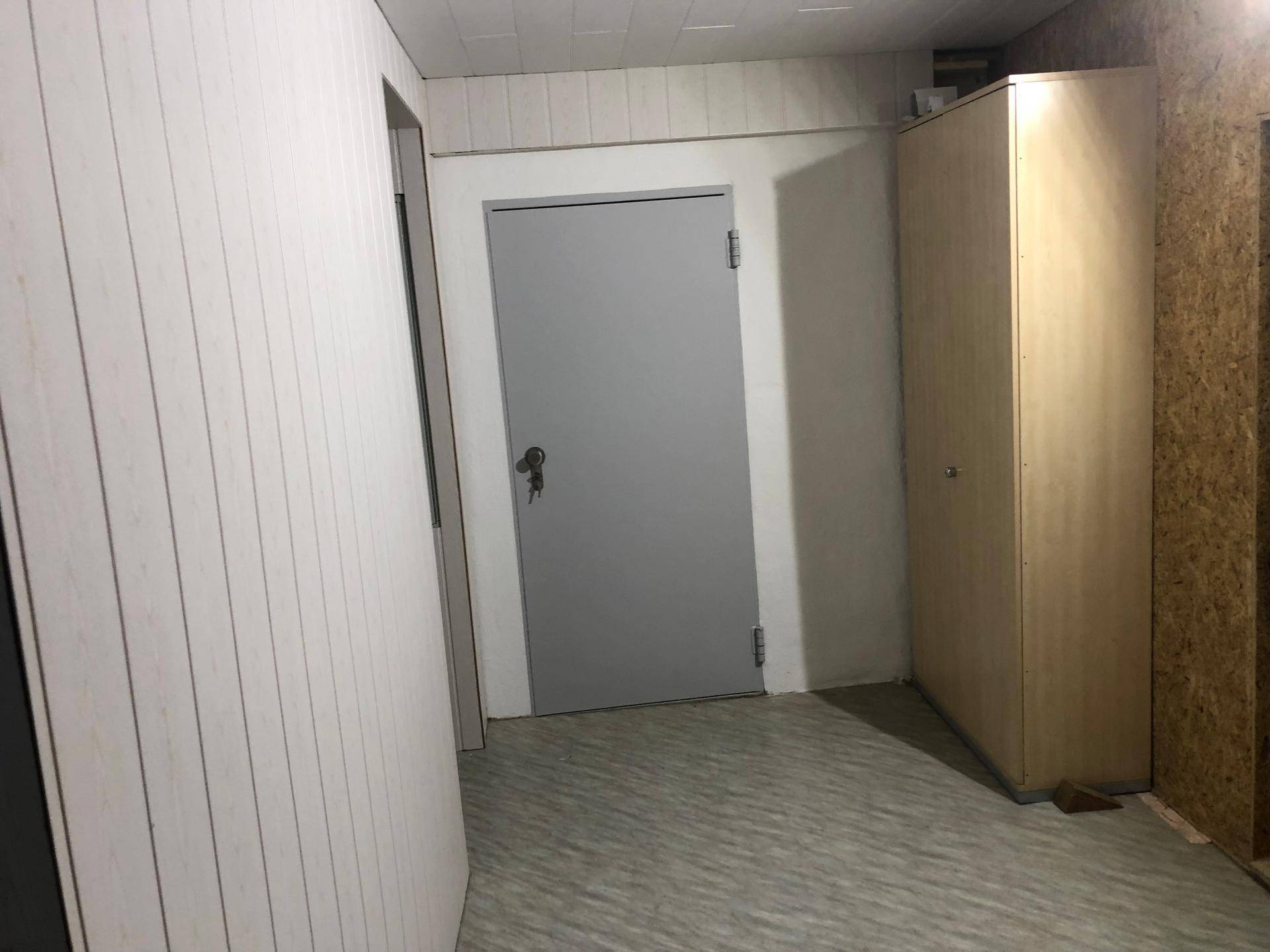 Einfacher Abstellraum mit Holzverkleidung an den Wänden und einem Schrank.
