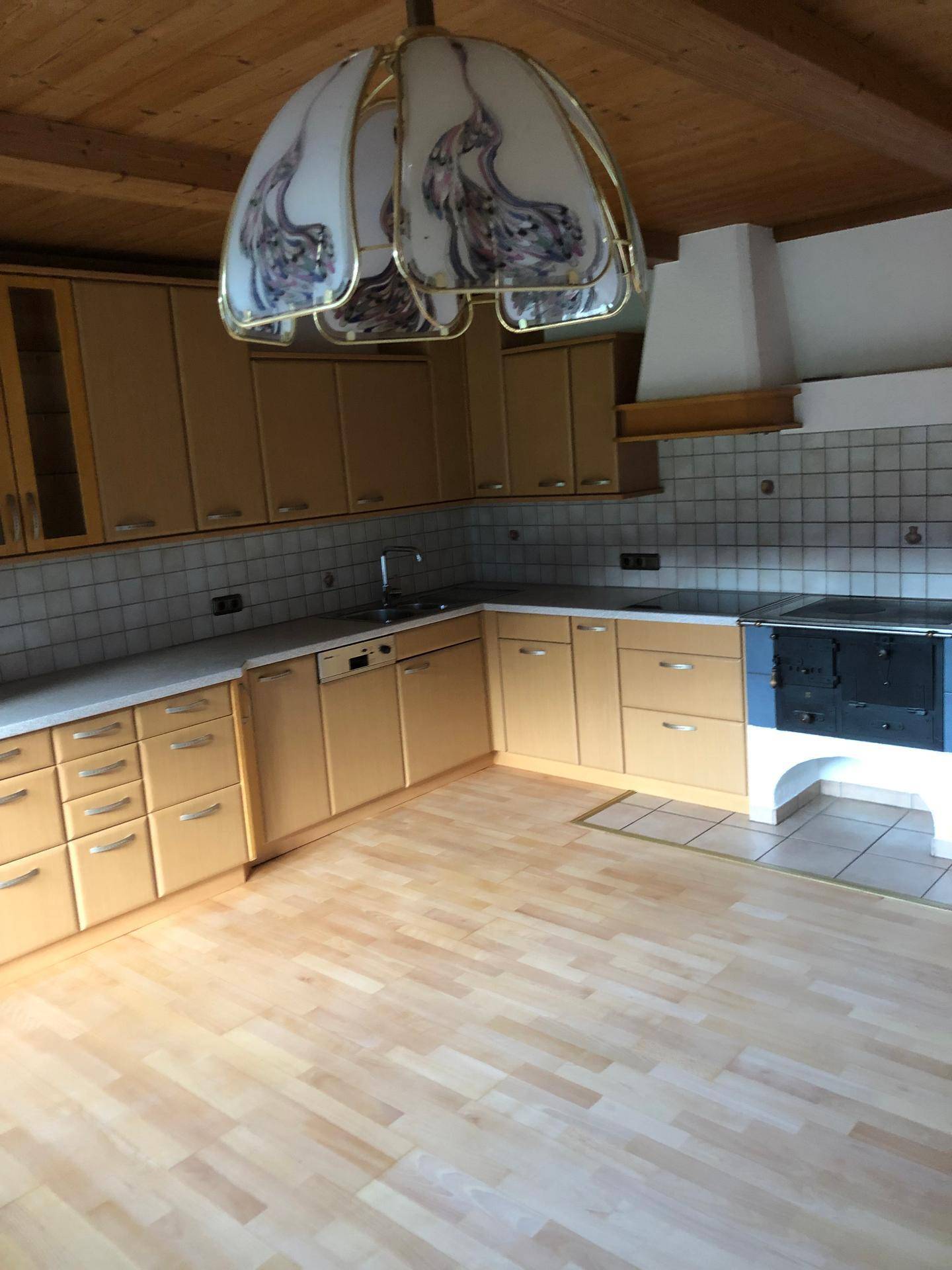 L-förmige Einbauküche mit hellen Holzfronten, Fliesenrückwand und traditionellem Herd.
