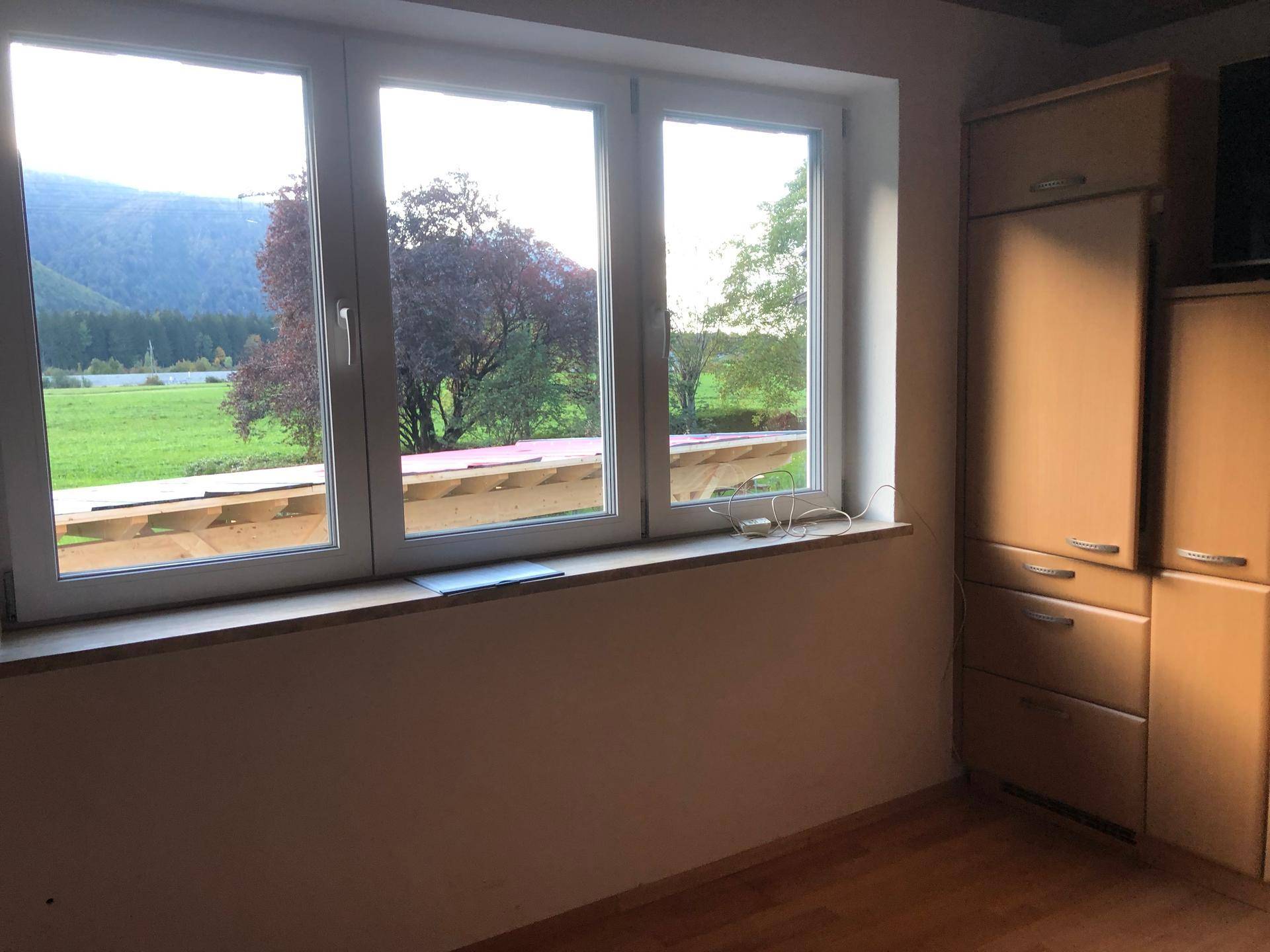 Fensterfront in der Küche bietet einen malerischen Blick auf Bäume und die umliegende Landschaft.