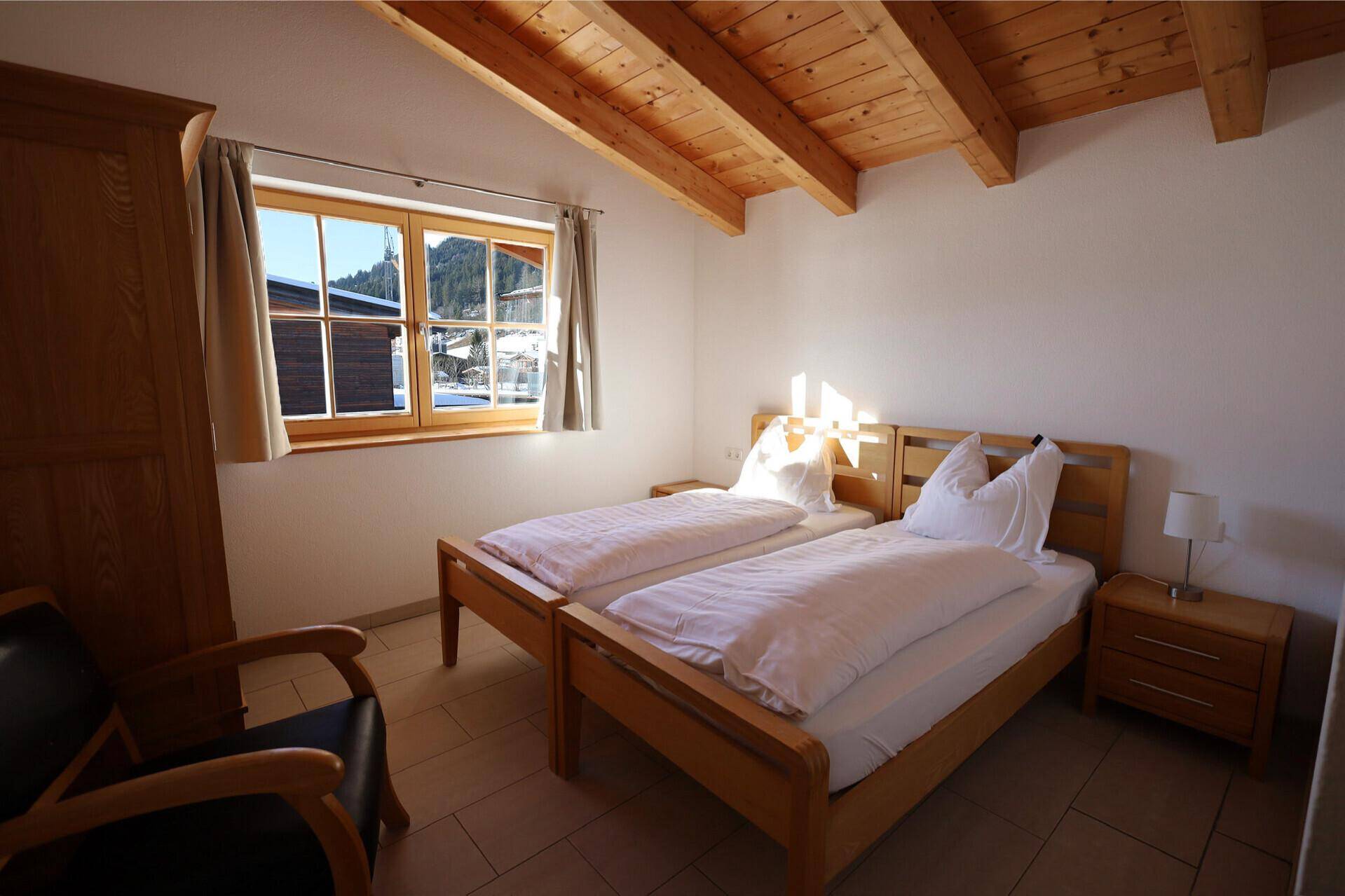 Gemütliches Schlafzimmer mit zwei Einzelbetten und sichtbaren Holzbalken an der Decke.
