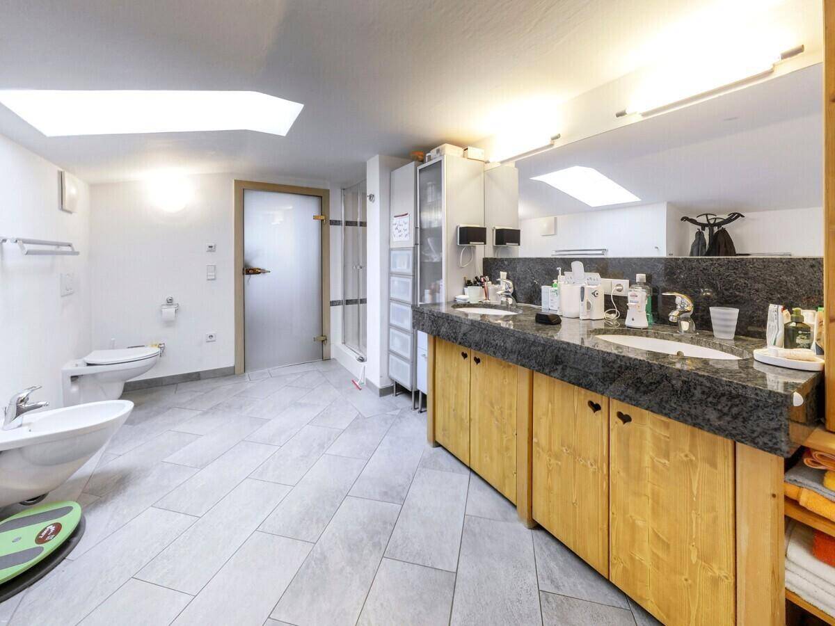 Geräumiges Badezimmer mit Doppelwaschbecken, Granitplatte, Bidet und Duschkabine.