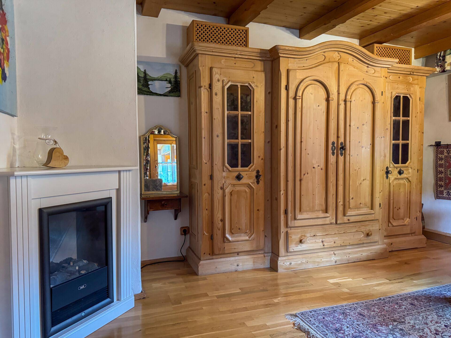 Heller Raum mit Holzboden, traditionellen Holzschränken und einem modernen Eckkamin.
