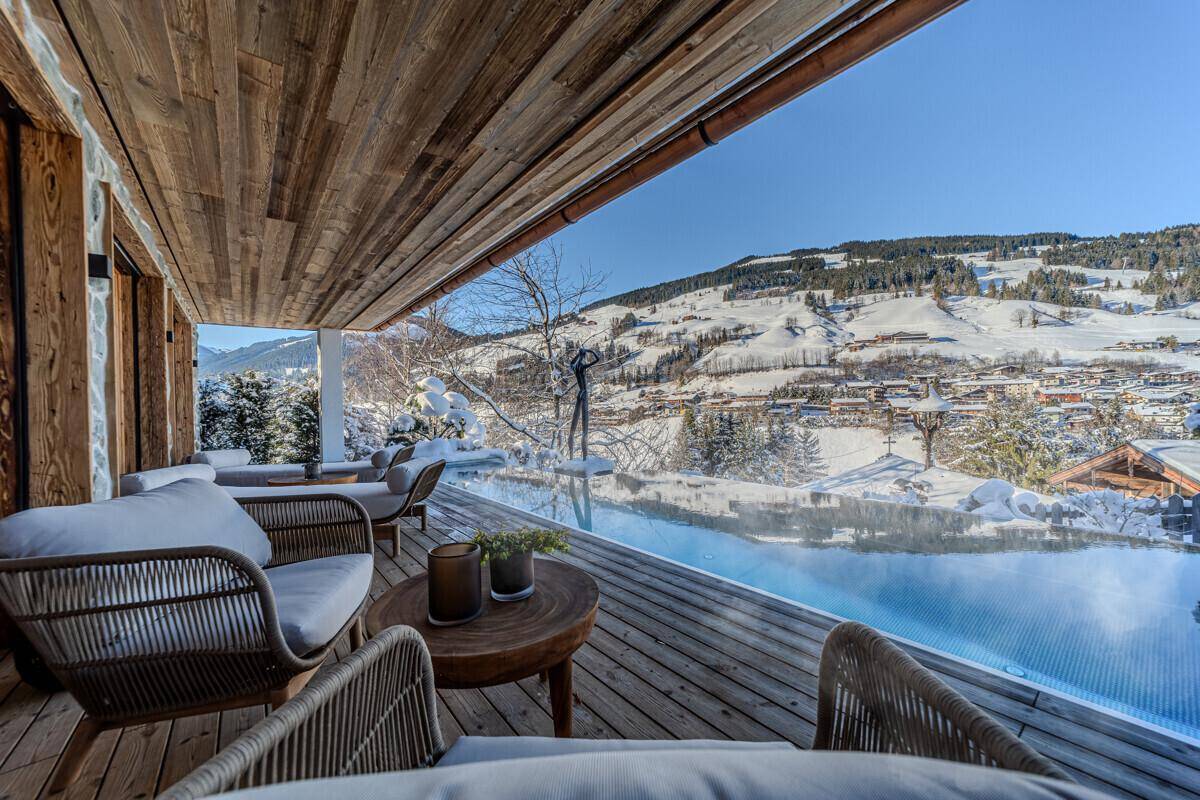 Exklusive Terrasse mit Infinity-Pool, bequemen Sitzgelegenheiten und atemberaubendem Bergblick.